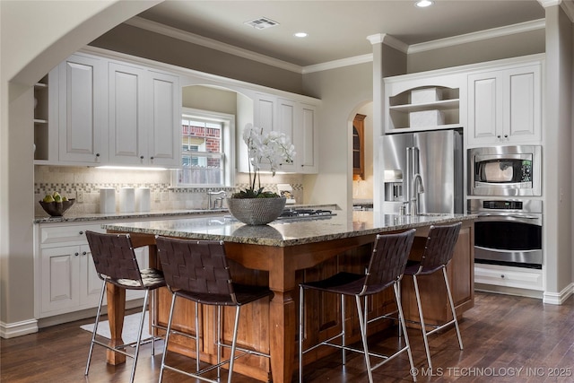 kitchen with white cabinets, light stone countertops, an island with sink, and stainless steel appliances