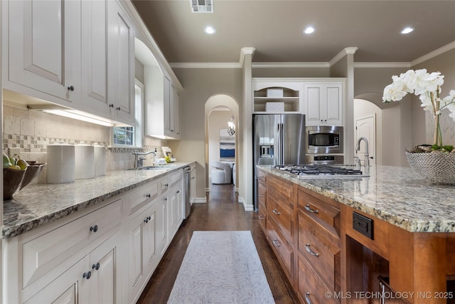 kitchen featuring tasteful backsplash, white cabinetry, light stone countertops, and appliances with stainless steel finishes