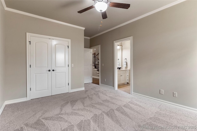 unfurnished bedroom featuring ornamental molding, light colored carpet, ceiling fan, connected bathroom, and a closet