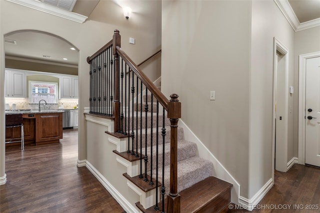 staircase featuring sink, wood-type flooring, and crown molding