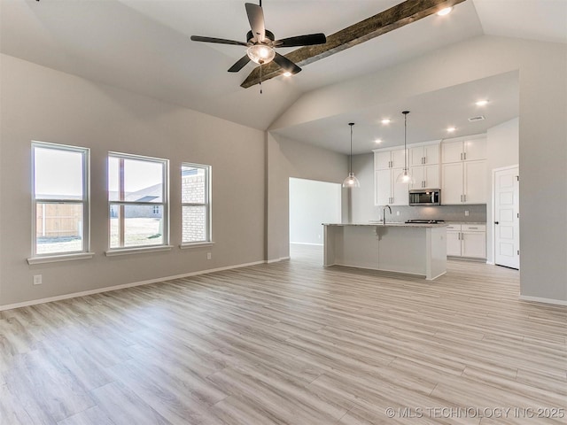 unfurnished living room featuring light hardwood / wood-style floors, vaulted ceiling, ceiling fan, and sink