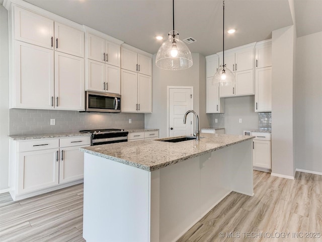 kitchen featuring white cabinets, a center island with sink, hanging light fixtures, and appliances with stainless steel finishes