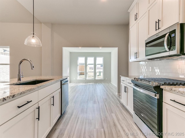 kitchen featuring light stone counters, stainless steel appliances, sink, pendant lighting, and white cabinets