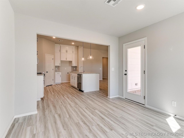 kitchen featuring pendant lighting, white cabinets, sink, stainless steel dishwasher, and light hardwood / wood-style floors