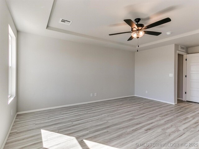 spare room with ceiling fan, a raised ceiling, and light hardwood / wood-style flooring