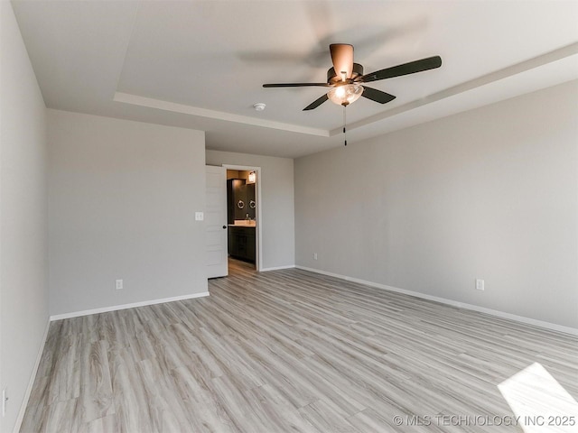 unfurnished room featuring light hardwood / wood-style floors, a raised ceiling, and ceiling fan