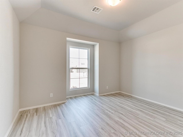 unfurnished room featuring light wood-type flooring and a tray ceiling