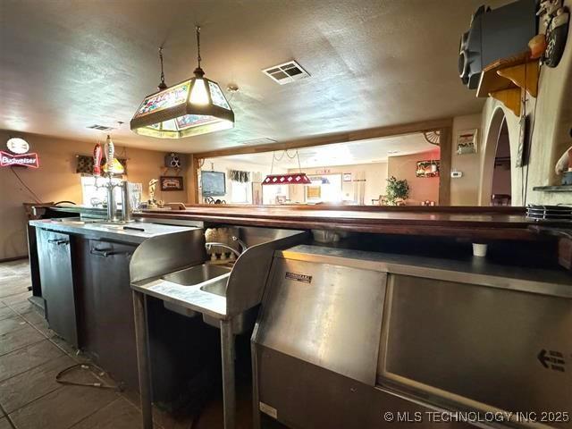 bar featuring decorative light fixtures and a textured ceiling