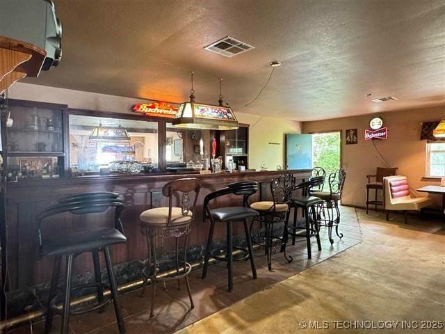 bar featuring a textured ceiling and concrete floors