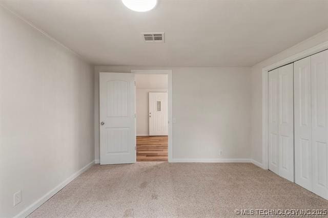 unfurnished bedroom featuring light carpet and a closet