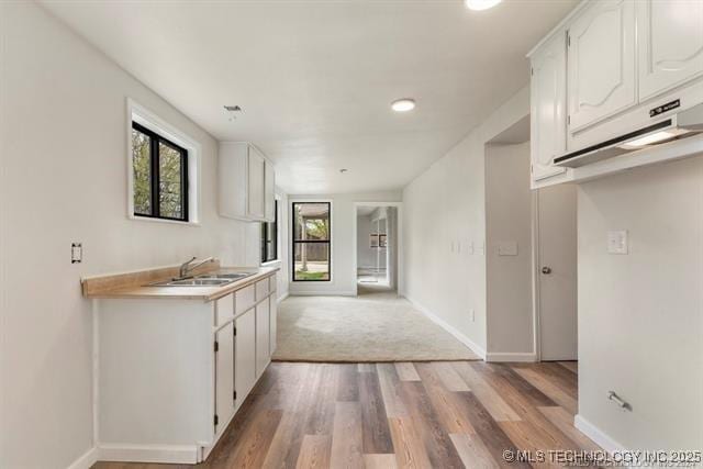 kitchen with white cabinets, sink, and light hardwood / wood-style flooring