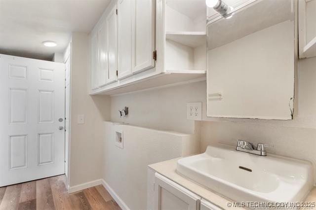 clothes washing area featuring washer hookup, light hardwood / wood-style flooring, and sink