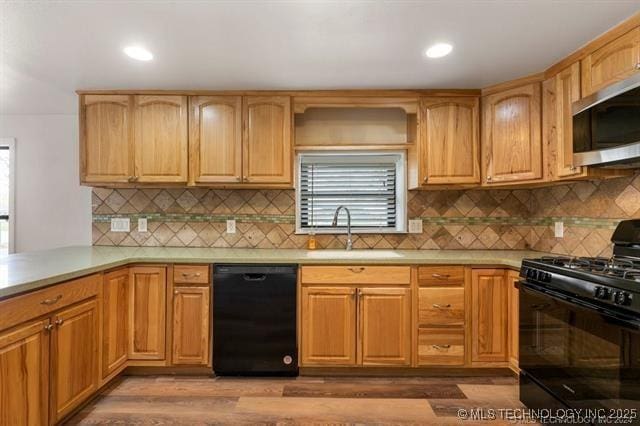 kitchen featuring black appliances, backsplash, sink, and hardwood / wood-style flooring