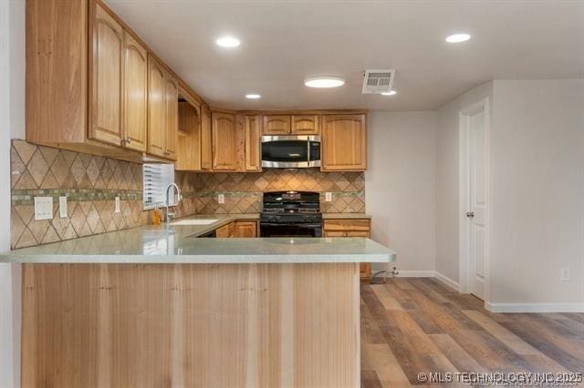 kitchen with sink, kitchen peninsula, wood-type flooring, decorative backsplash, and black range