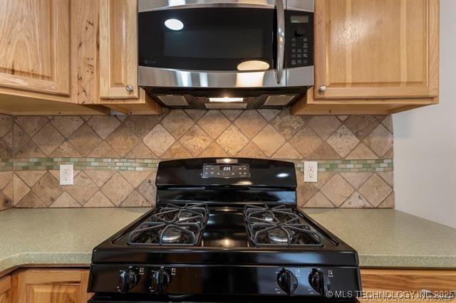 kitchen featuring black range with gas stovetop, decorative backsplash, and light brown cabinets