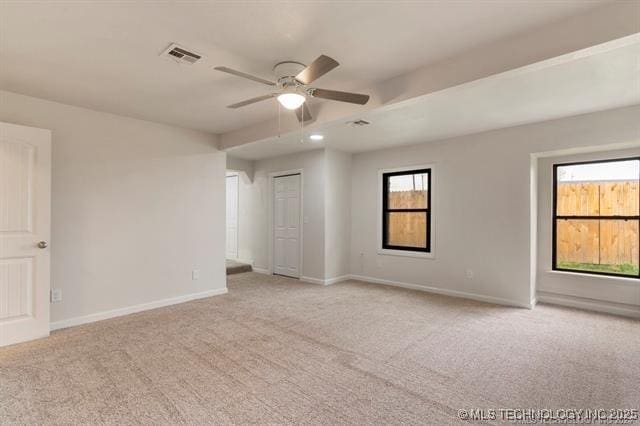 spare room featuring light colored carpet, plenty of natural light, and ceiling fan