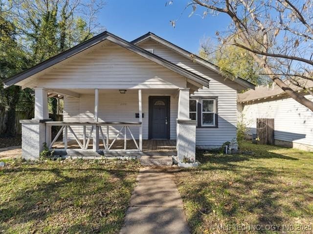 bungalow with covered porch and a front lawn