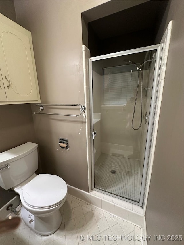 bathroom with tile patterned floors, toilet, and walk in shower