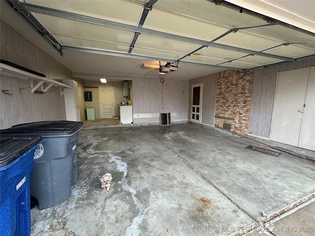 garage with a garage door opener, wooden walls, and electric panel