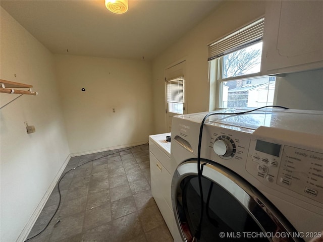 clothes washing area featuring cabinets and washing machine and clothes dryer