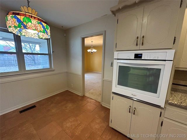 kitchen featuring decorative light fixtures, a chandelier, oven, and white cabinets