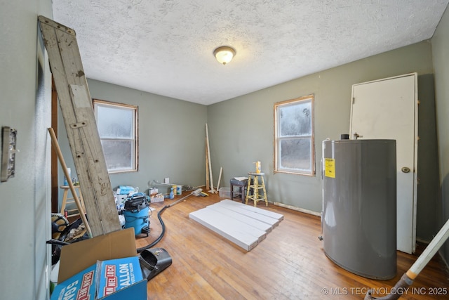 misc room featuring hardwood / wood-style flooring, plenty of natural light, a textured ceiling, and water heater