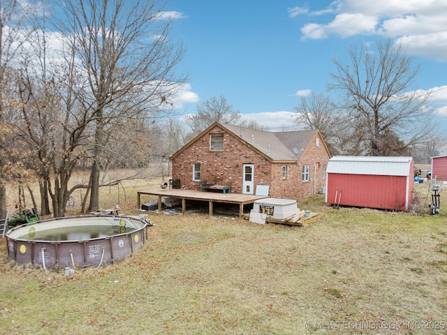 back of house with a pool side deck, a shed, and a yard