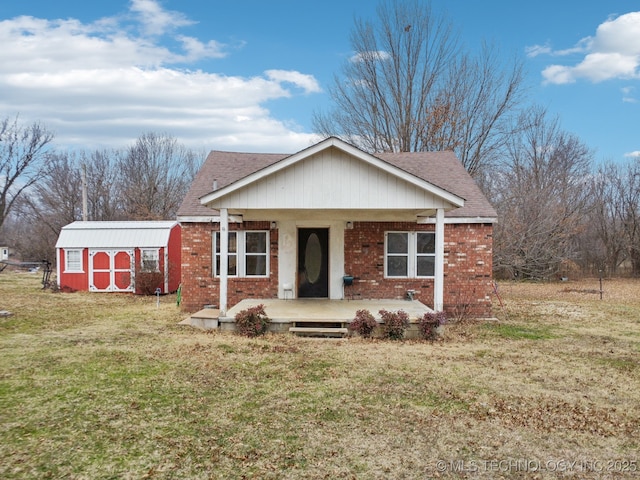 view of front of home with a porch, a shed, and a front lawn