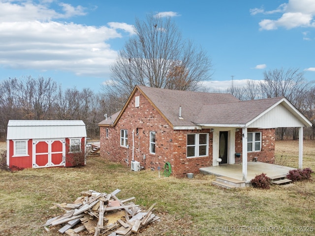 view of front facade with a deck, central AC unit, a front yard, and a storage shed