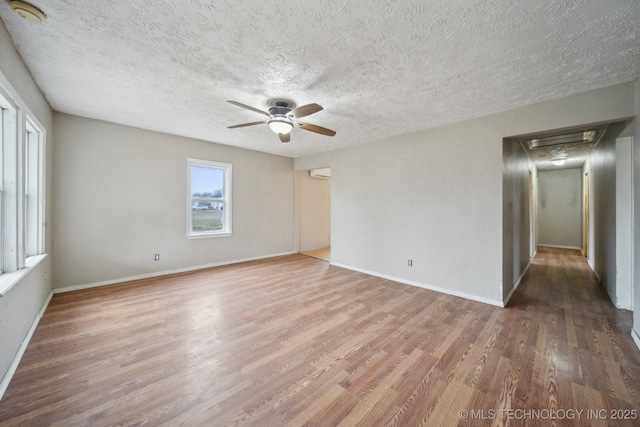 empty room featuring ceiling fan, hardwood / wood-style floors, a wall mounted air conditioner, and a textured ceiling