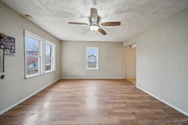 empty room with hardwood / wood-style floors, ceiling fan, a healthy amount of sunlight, and a textured ceiling