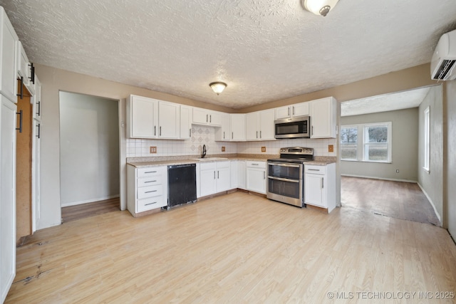 kitchen with white cabinetry, sink, stainless steel appliances, and light hardwood / wood-style floors