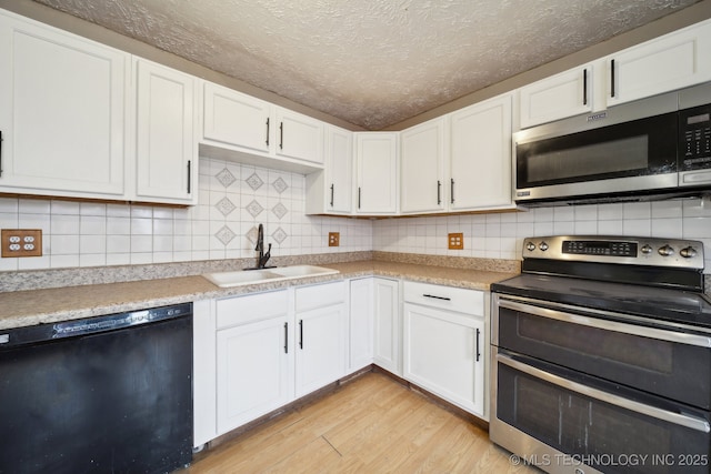 kitchen with white cabinets, sink, stainless steel appliances, and light hardwood / wood-style flooring