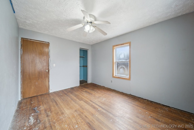 unfurnished bedroom featuring ceiling fan, dark wood-type flooring, and a textured ceiling