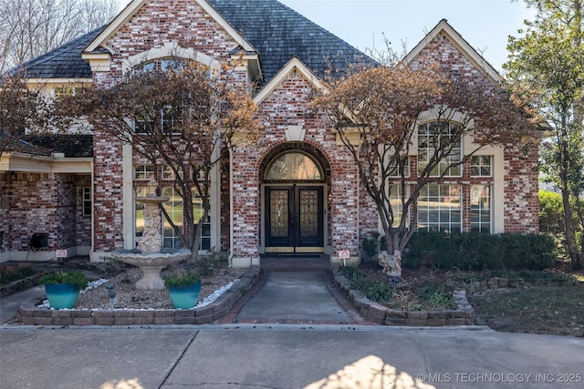 view of exterior entry featuring a high end roof, french doors, and brick siding