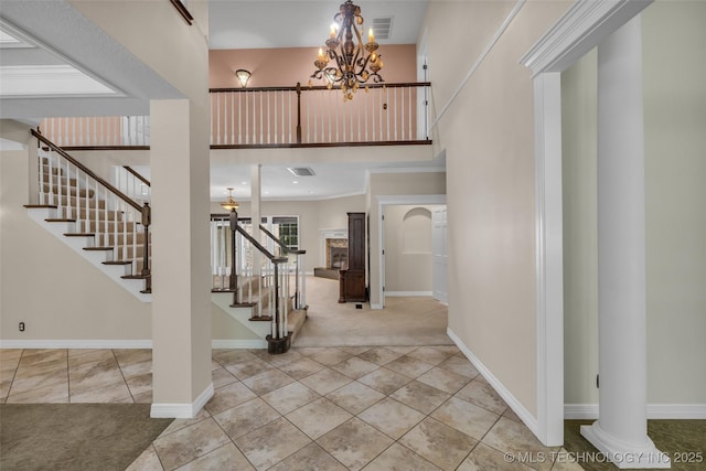 tiled entrance foyer featuring decorative columns and a notable chandelier