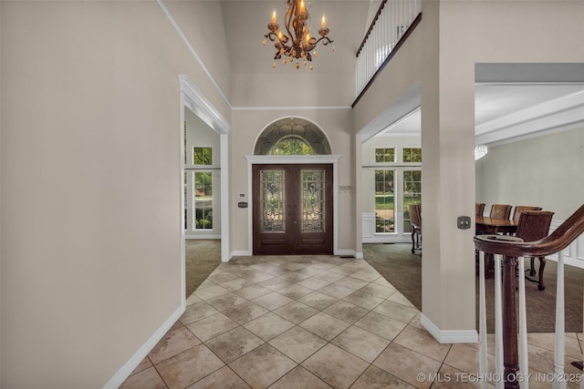 foyer with light tile patterned flooring, french doors, a high ceiling, and a chandelier