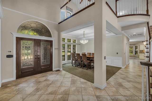 entryway with a chandelier, a towering ceiling, light carpet, and french doors