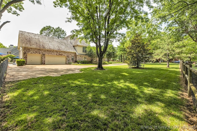 view of yard featuring driveway, an attached garage, and fence