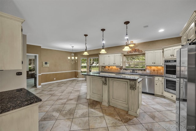 kitchen with pendant lighting, stainless steel appliances, dark stone countertops, and a center island