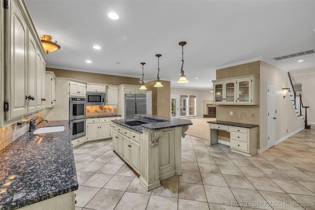 kitchen with built in appliances, a sink, hanging light fixtures, a center island, and glass insert cabinets