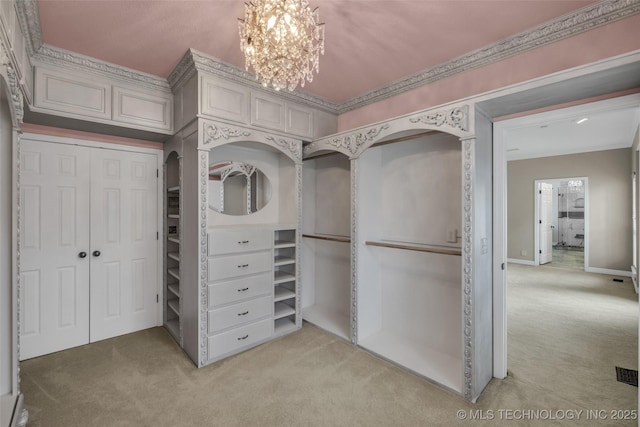 walk in closet featuring a chandelier and light colored carpet