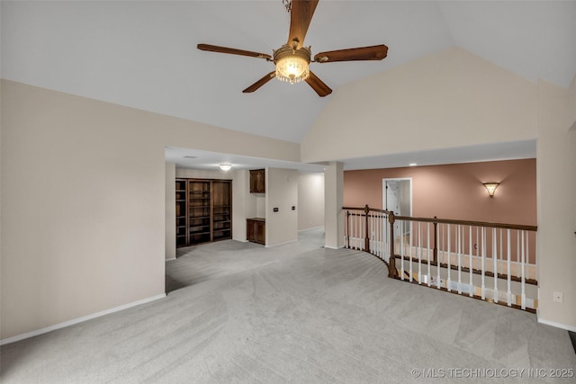 empty room with baseboards, high vaulted ceiling, and light colored carpet