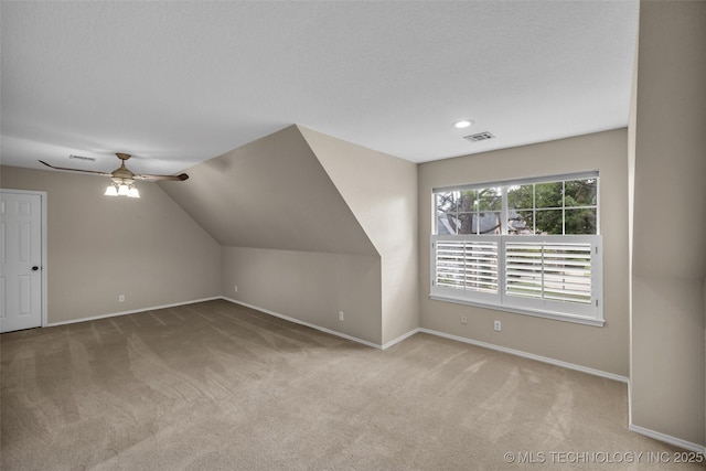 bonus room with a textured ceiling, light colored carpet, vaulted ceiling, and ceiling fan