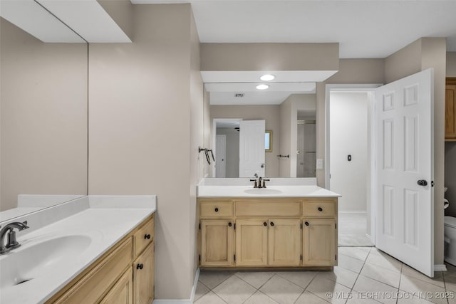 full bath with toilet, two vanities, a sink, and tile patterned floors