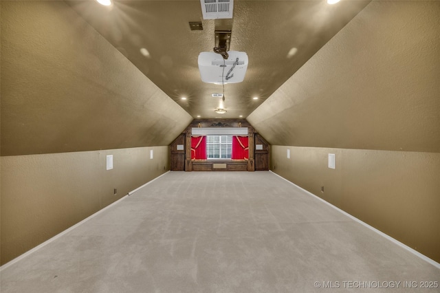 additional living space featuring carpet, visible vents, vaulted ceiling, a textured ceiling, and baseboards