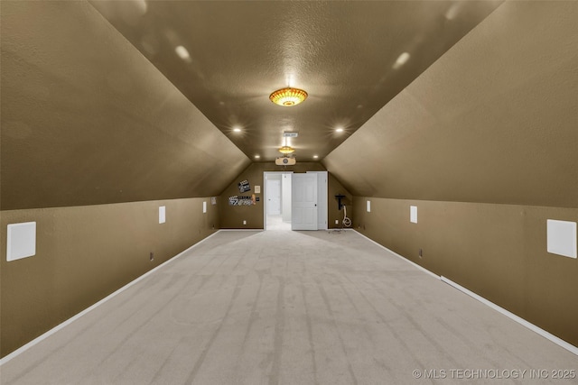 bonus room with lofted ceiling, light colored carpet, a textured ceiling, and baseboards