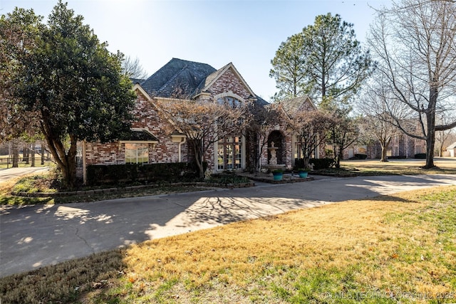 view of front of property featuring concrete driveway, brick siding, and a front lawn