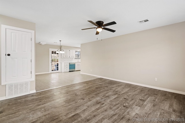 unfurnished living room featuring ceiling fan with notable chandelier, light hardwood / wood-style floors, and beverage cooler