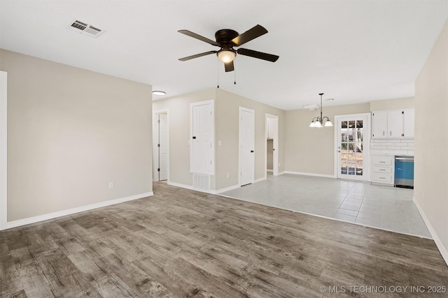 unfurnished living room with ceiling fan with notable chandelier and light tile patterned floors